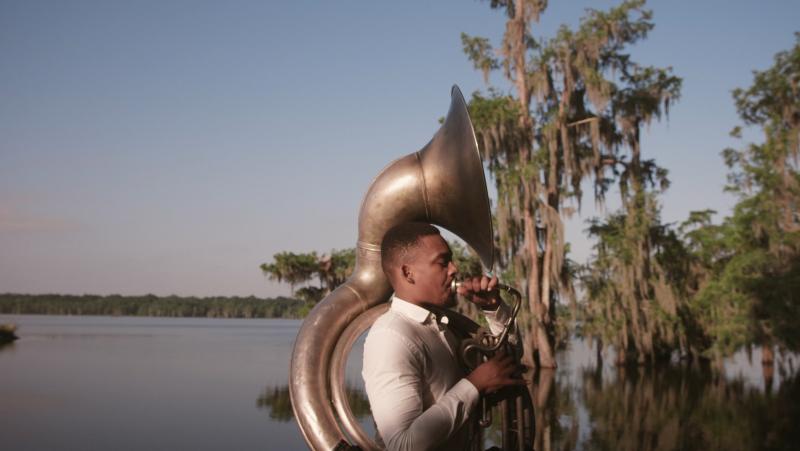 Homme jouant du cor en extérieur lac et forêt