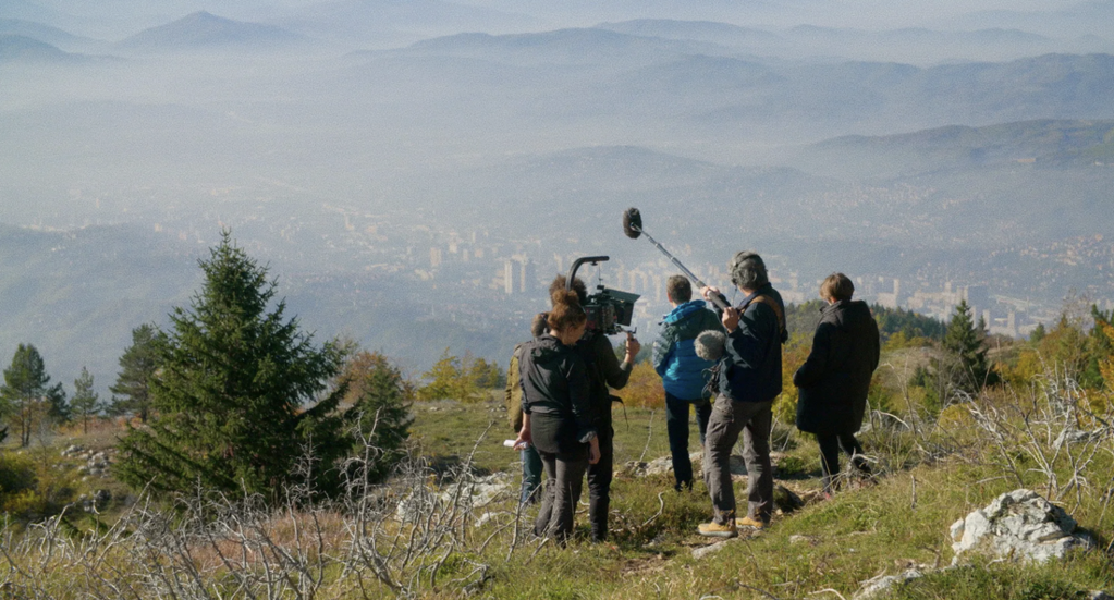 Equipe de tournage de dos sur une montagne et vue sur une ville dans la brume